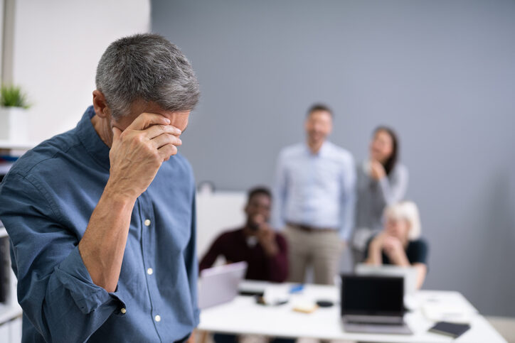 Collega's praten achter de rug van deze man om.